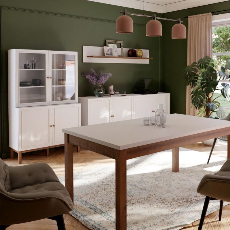 Modern dining room with a wooden table, white cabinets, and green walls.