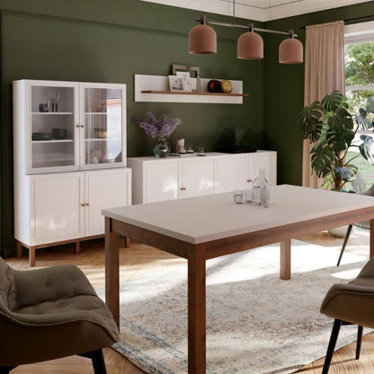 Modern dining room with a wooden table, white cabinets, and green walls.