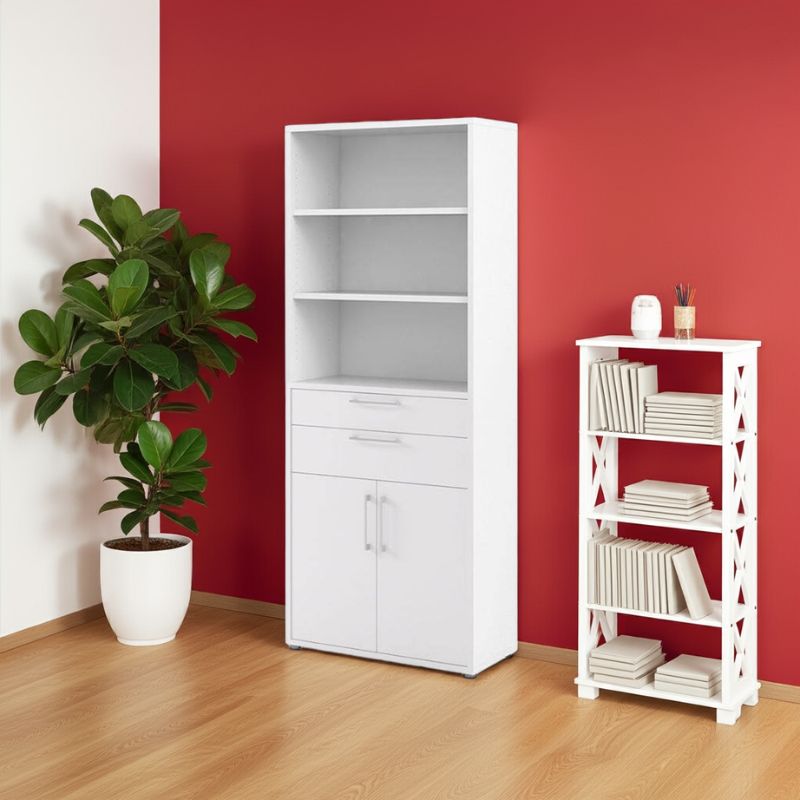 White bookshelf with drawers and cupboard against a red wall with a plant on a wooden floor.