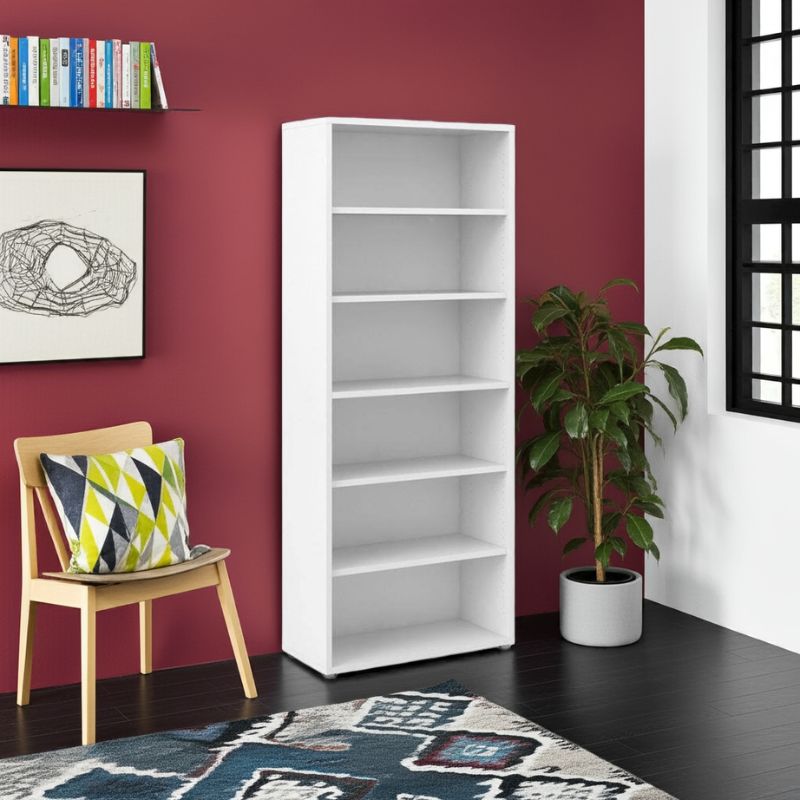 White bookshelf against a red wall with a chair, plant, and books in a room.