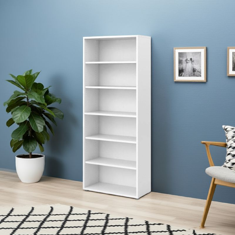 White bookshelf against a blue wall with a plant and chair in a room.