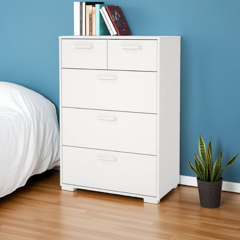 White dresser with books against a blue wall in a bedroom setting